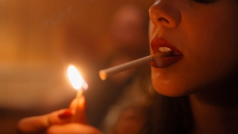 Nahaufnahme: eine Zigarette wird an einer Streichholzflamme angezündet.